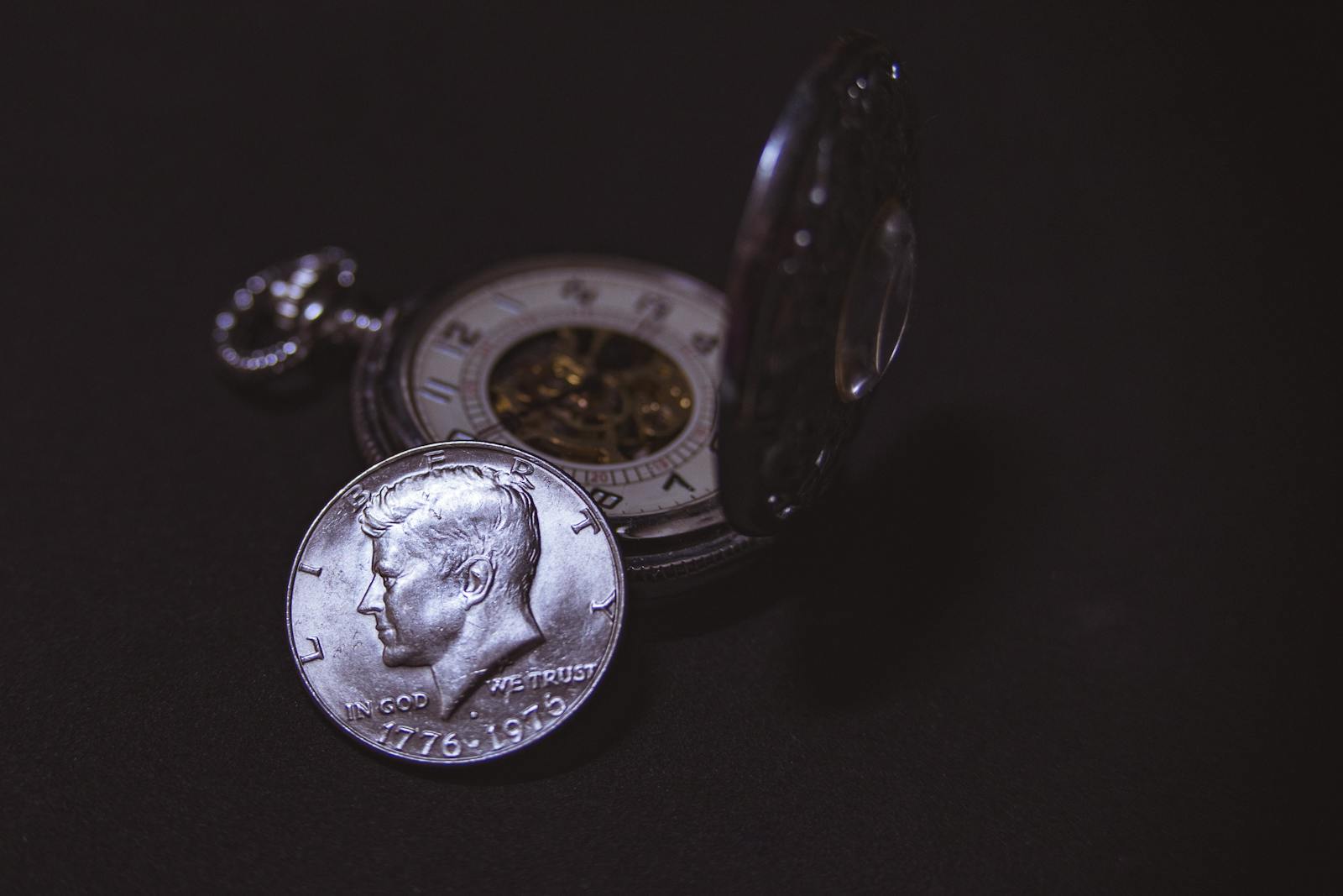 Close-up of a vintage silver coin with a pocket watch, symbolizing time and wealth.