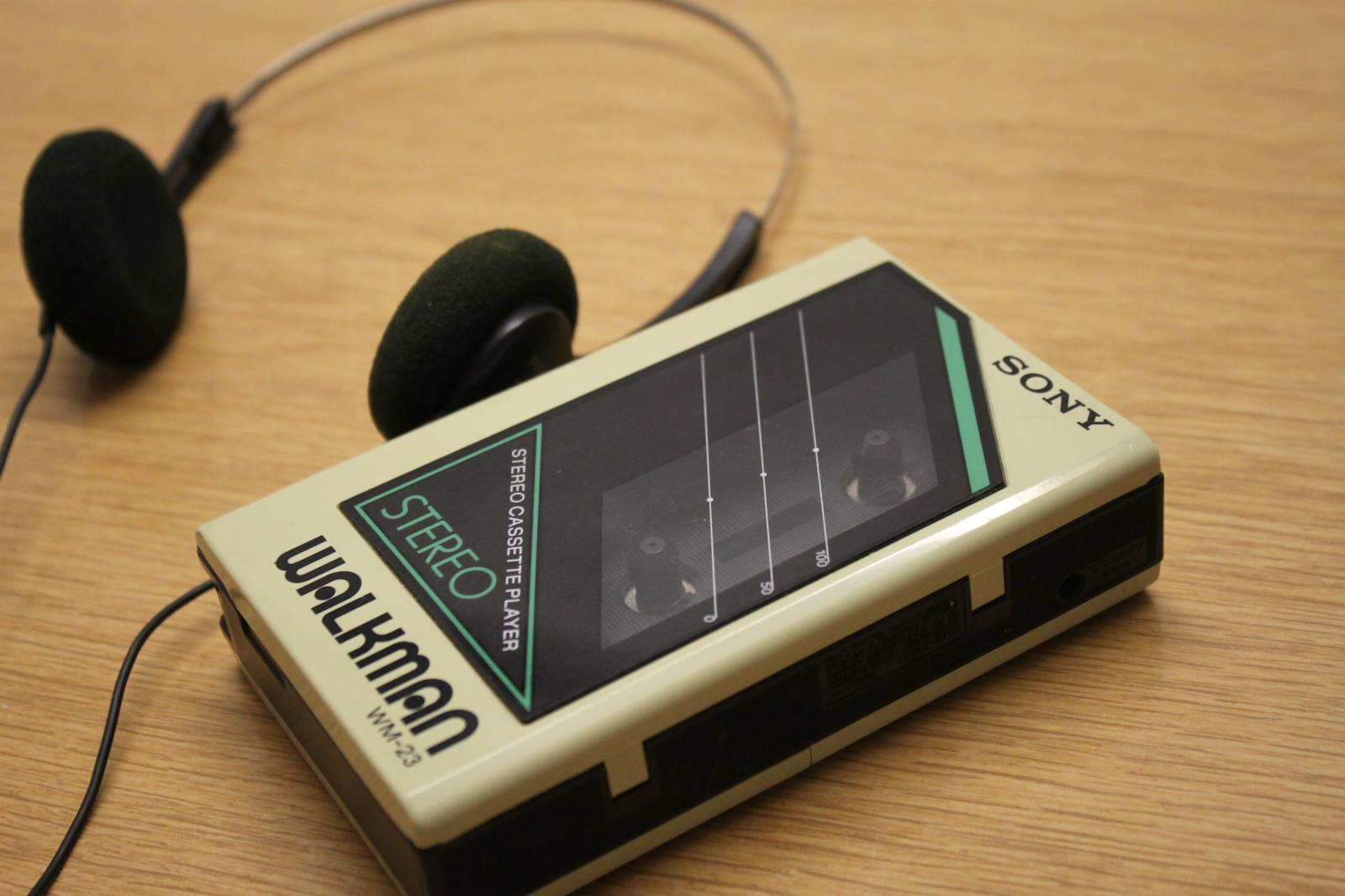 Classic Sony Walkman stereo cassette player with retro headphones on wooden surface.