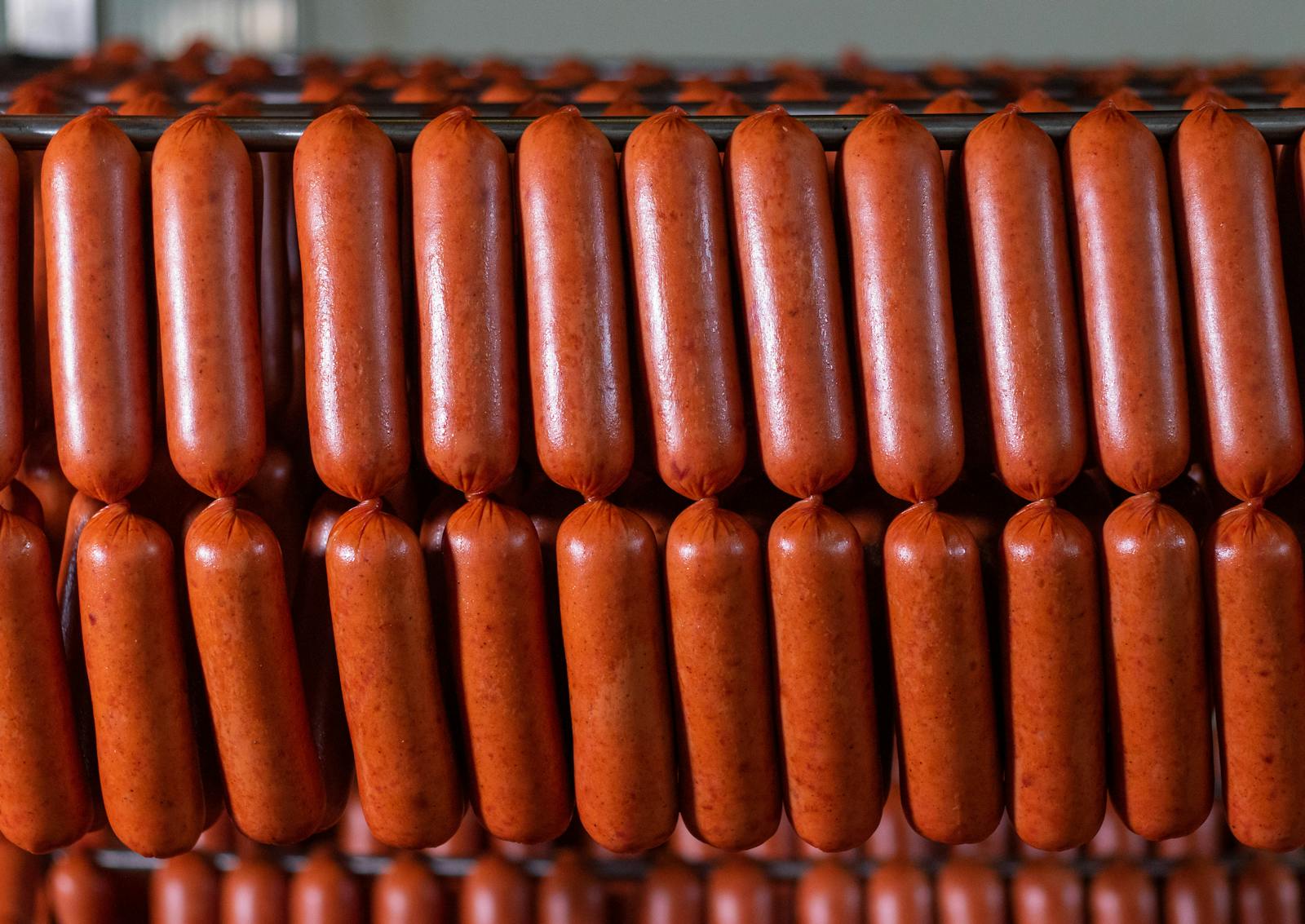 Close-up view of neatly arranged sausages hanging in a production facility.