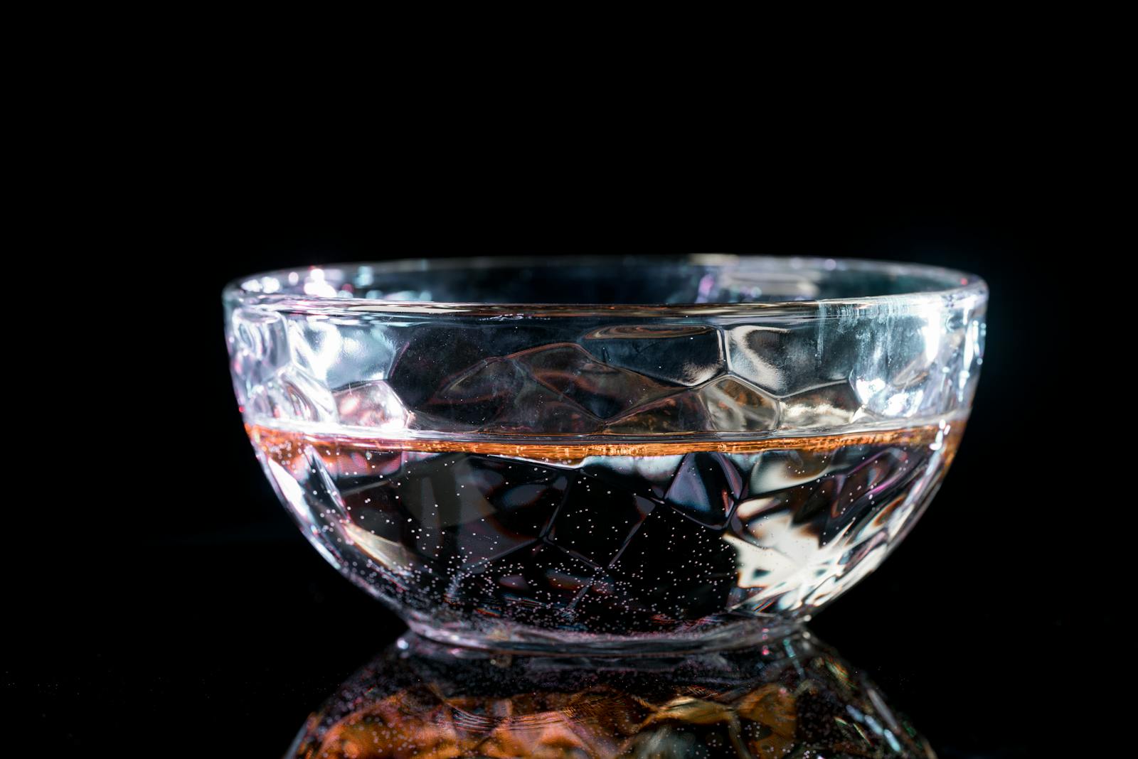 Elegant crystal glass bowl filled with water, highlighted against a dark backdrop.