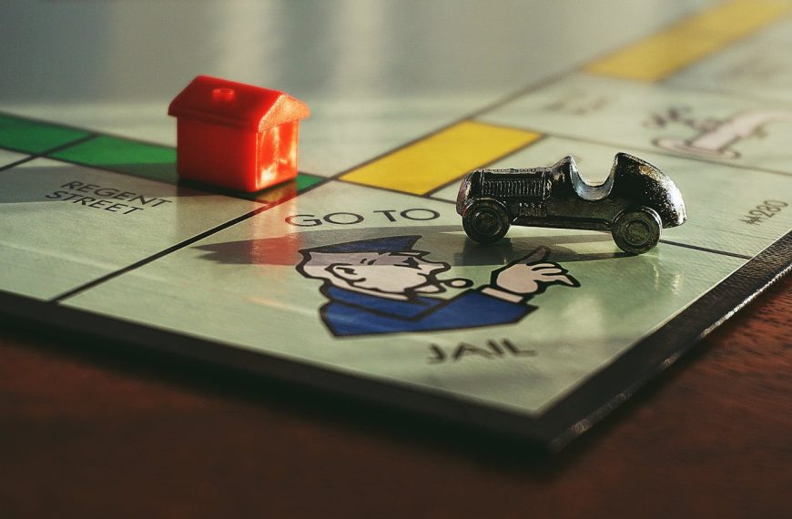 Close-up shot of a Monopoly board game featuring a toy car and a red house on 'Go to Jail'.