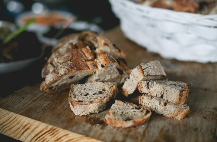 Close-up of freshly sliced artisan bread on a rustic wooden board, perfect for breakfast or snacks.