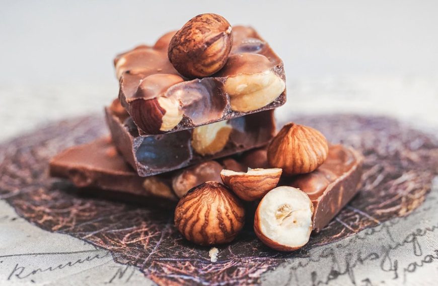 Close-up of stacked chocolate bars with whole hazelnuts, perfect for sweet indulgence.