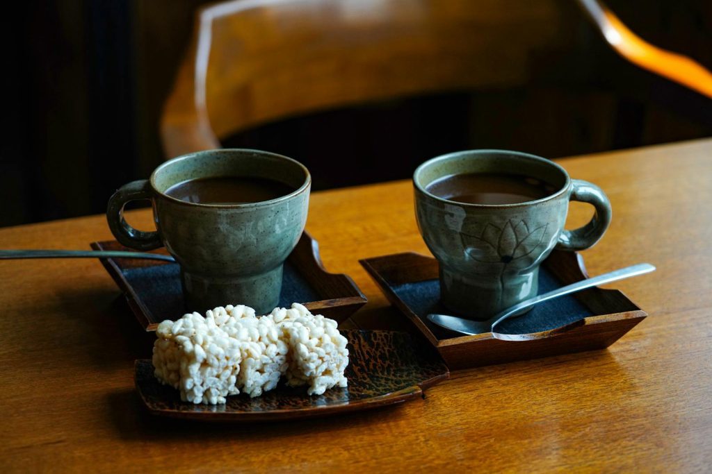 Warm atmosphere with two ceramic cups of coffee and snacks on wooden table.