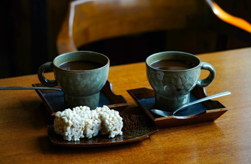 Warm atmosphere with two ceramic cups of coffee and snacks on wooden table.