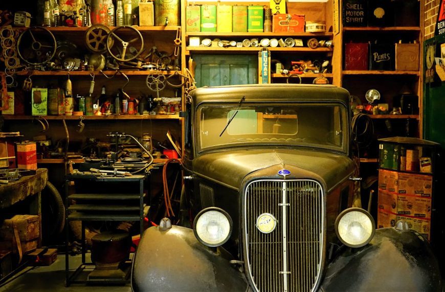 A vintage car surrounded by classic tools and equipment in a workshop setting.