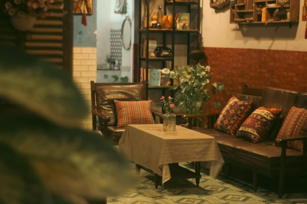 Inviting vintage room with armchairs, decorative pillows, and a table with a flower vase, offering a warm atmosphere.