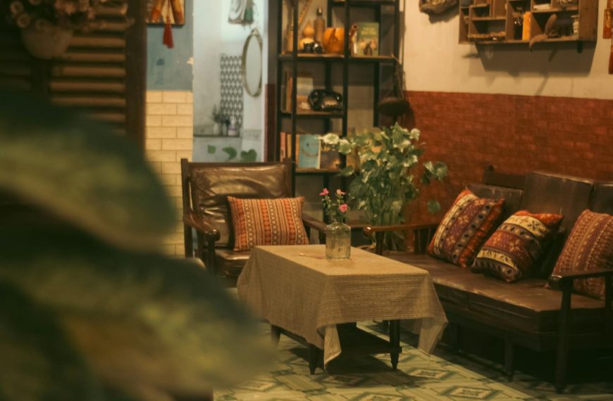 Inviting vintage room with armchairs, decorative pillows, and a table with a flower vase, offering a warm atmosphere.