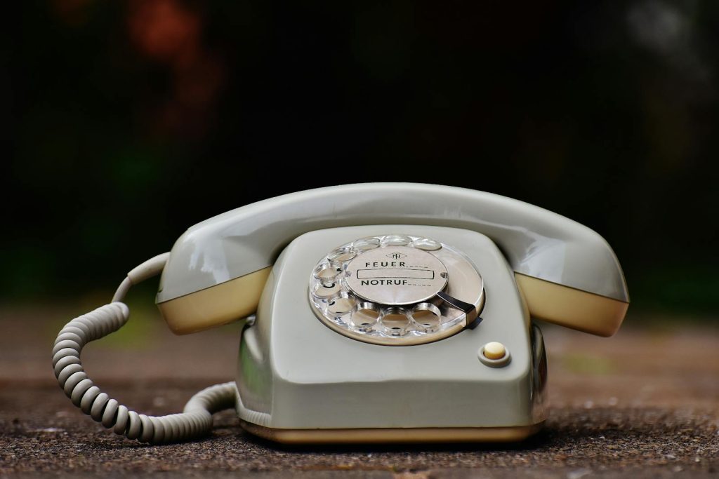 Close-up of a vintage rotary dial telephone with a nostalgic design on a wooden surface.