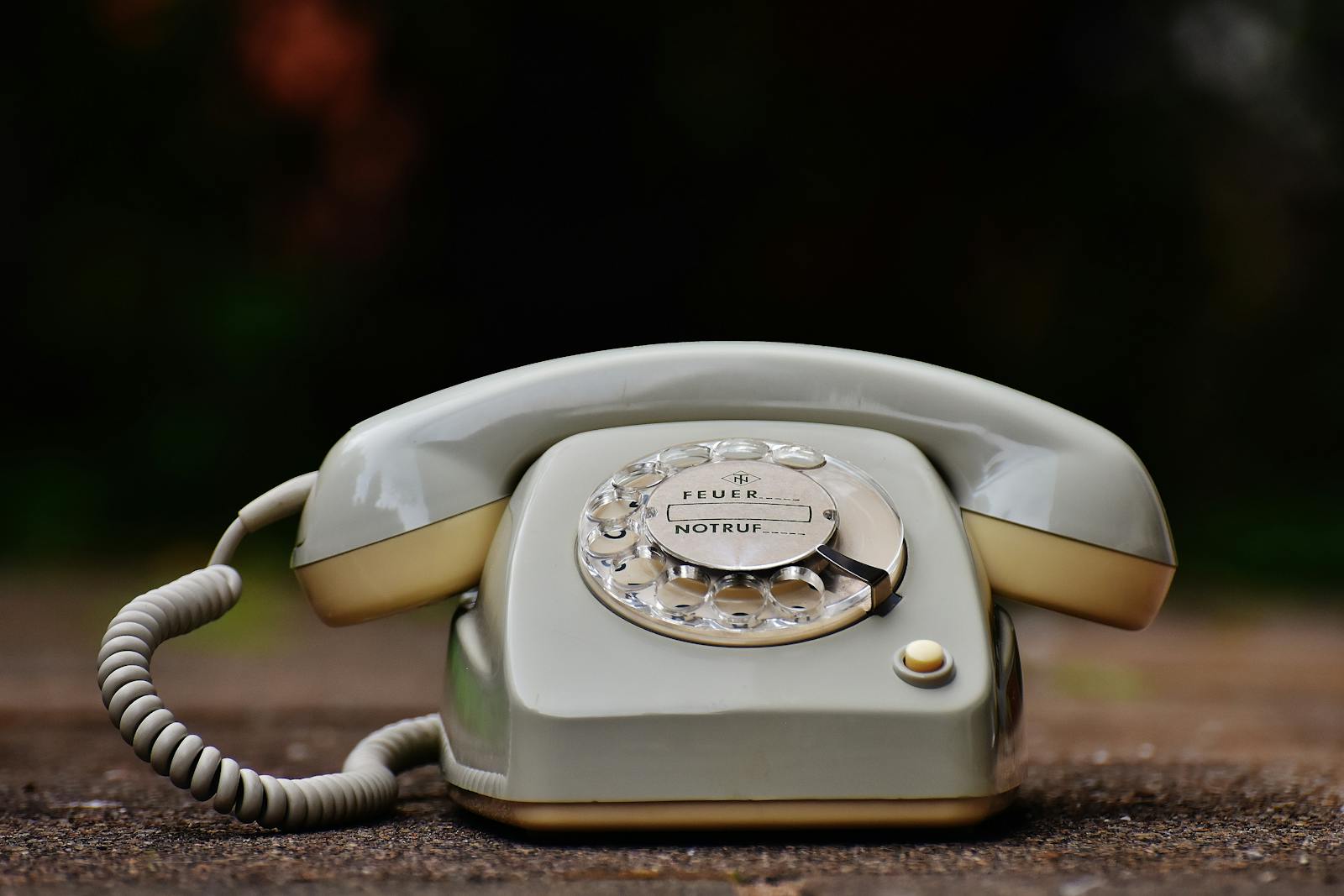 Close-up of a vintage rotary dial telephone with a nostalgic design on a wooden surface.