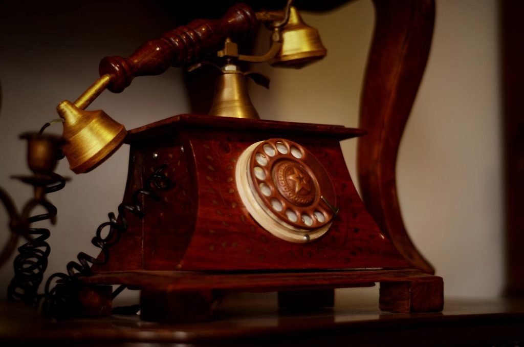 A classic wooden rotary telephone with a brass handset, exhibiting vintage charm.