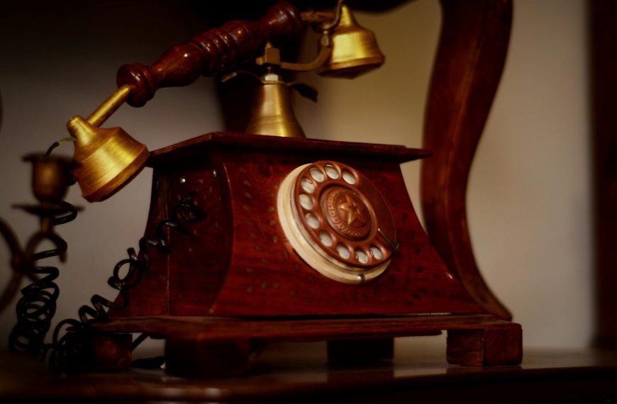A classic wooden rotary telephone with a brass handset, exhibiting vintage charm.
