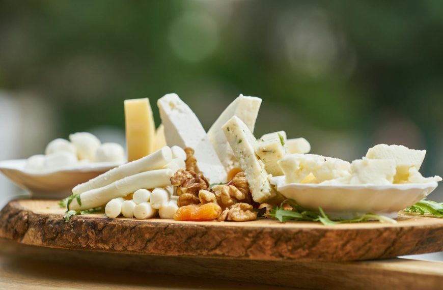 A delicious assortment of cheese and nuts on a rustic wooden board, perfect for appetizers.