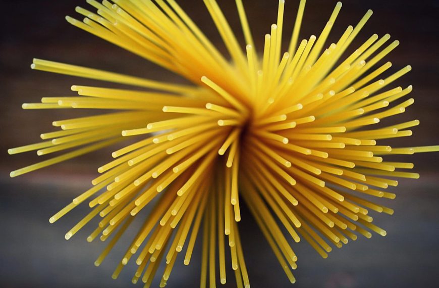 Close-up shot of uncooked spaghetti viewed from above featuring a vibrant golden color.