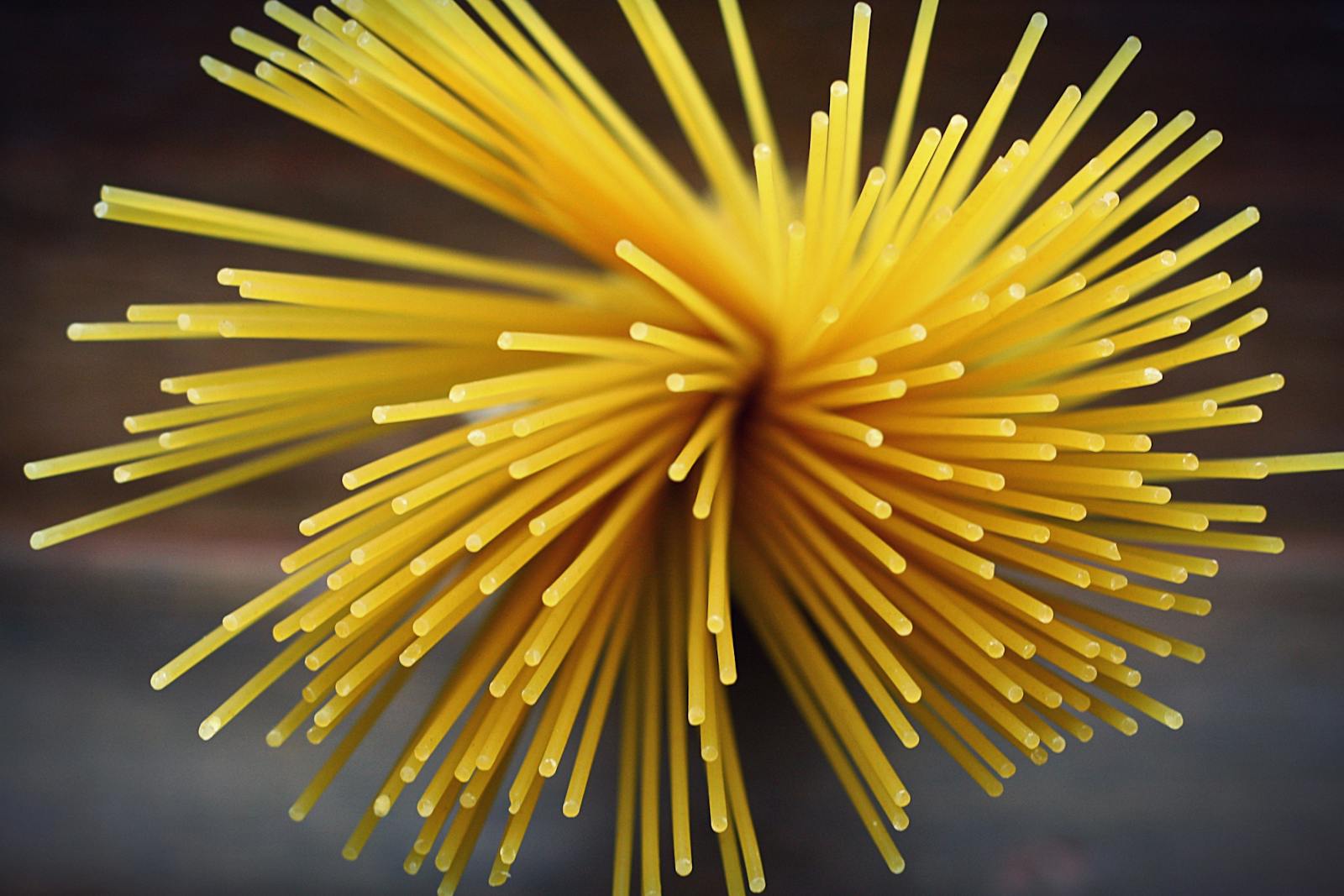 Close-up shot of uncooked spaghetti viewed from above featuring a vibrant golden color.