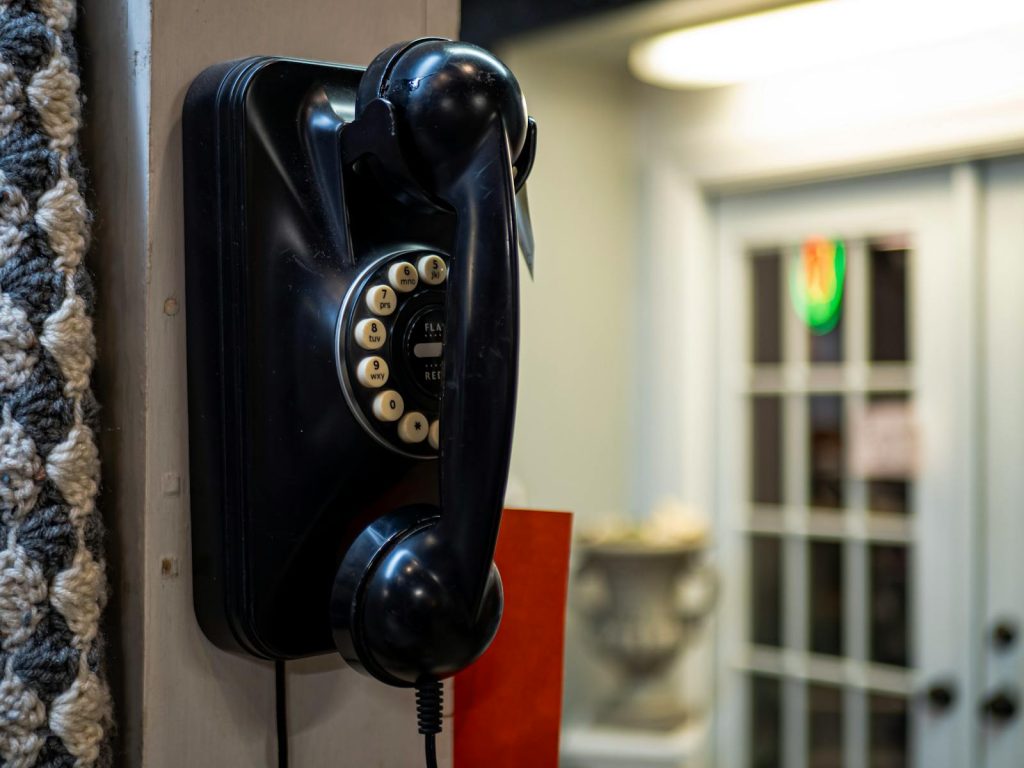 A classic black rotary telephone mounted indoors, showcasing vintage technology.