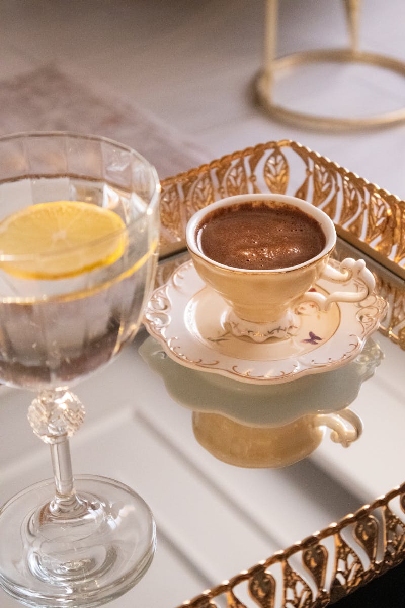 Luxurious coffee and lemon water on ornate reflective tray.