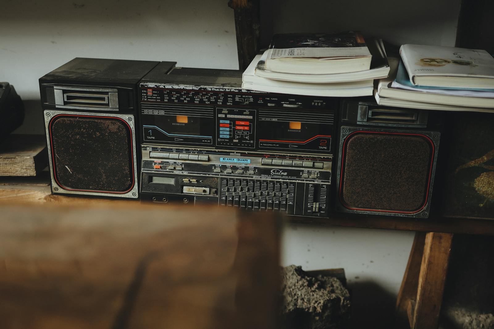 A classic retro boombox placed on a shelf, accompanied by books, creating a nostalgic ambiance.