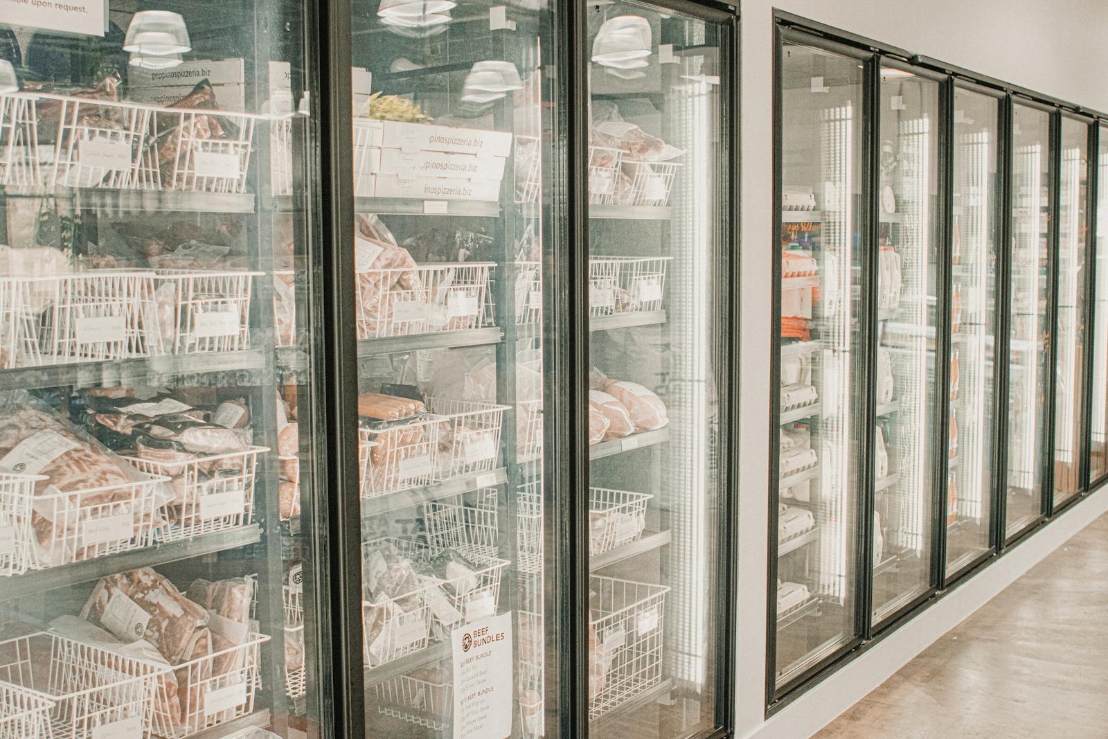 Frozen meats in a retail freezer with transparent doors and organized sections.