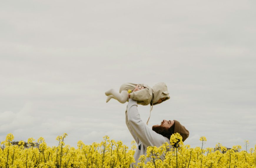 a person holding a baby in a field of yellow flowers