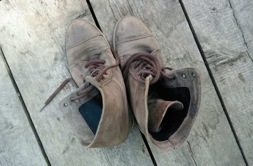 a pair of brown shoes sitting on top of a wooden deck
