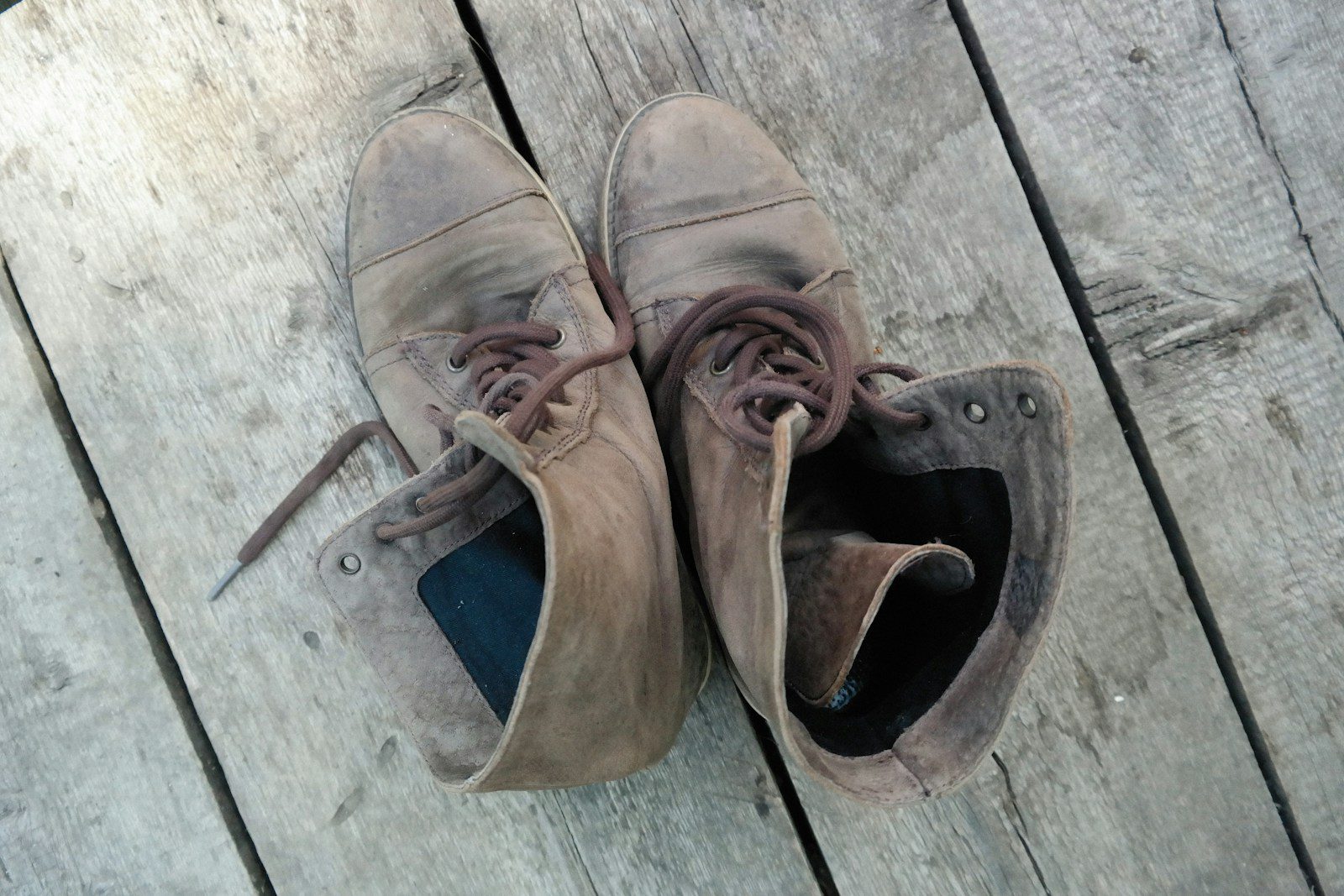 a pair of brown shoes sitting on top of a wooden deck
