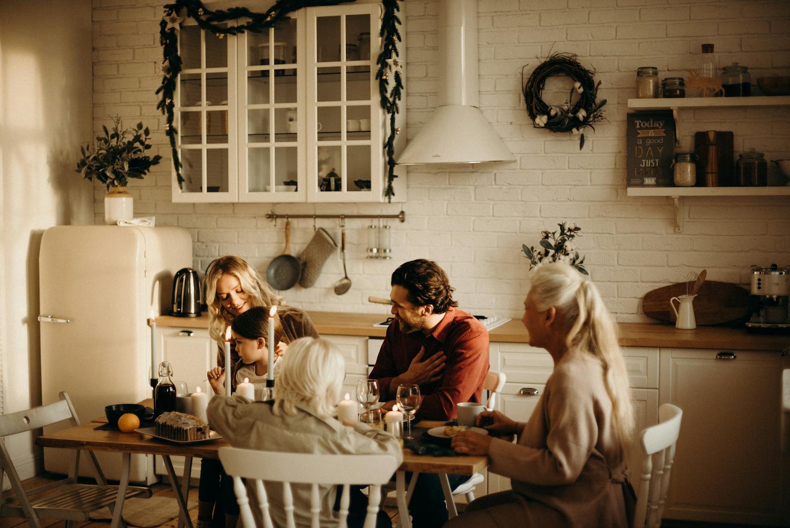 Family enjoying a holiday meal in a cozy, warmly lit dining room setting with candles and festive decor.