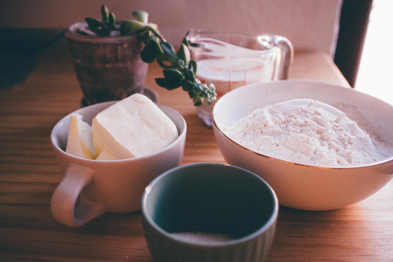 A cozy setup of baking ingredients including butter, flour, and a measuring cup on a wooden table.