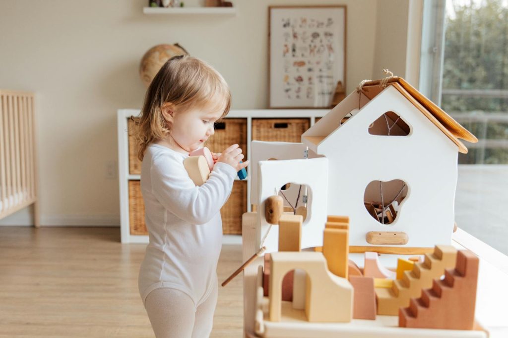 Cute toddler engaging with wooden toys in a bright indoor setting.