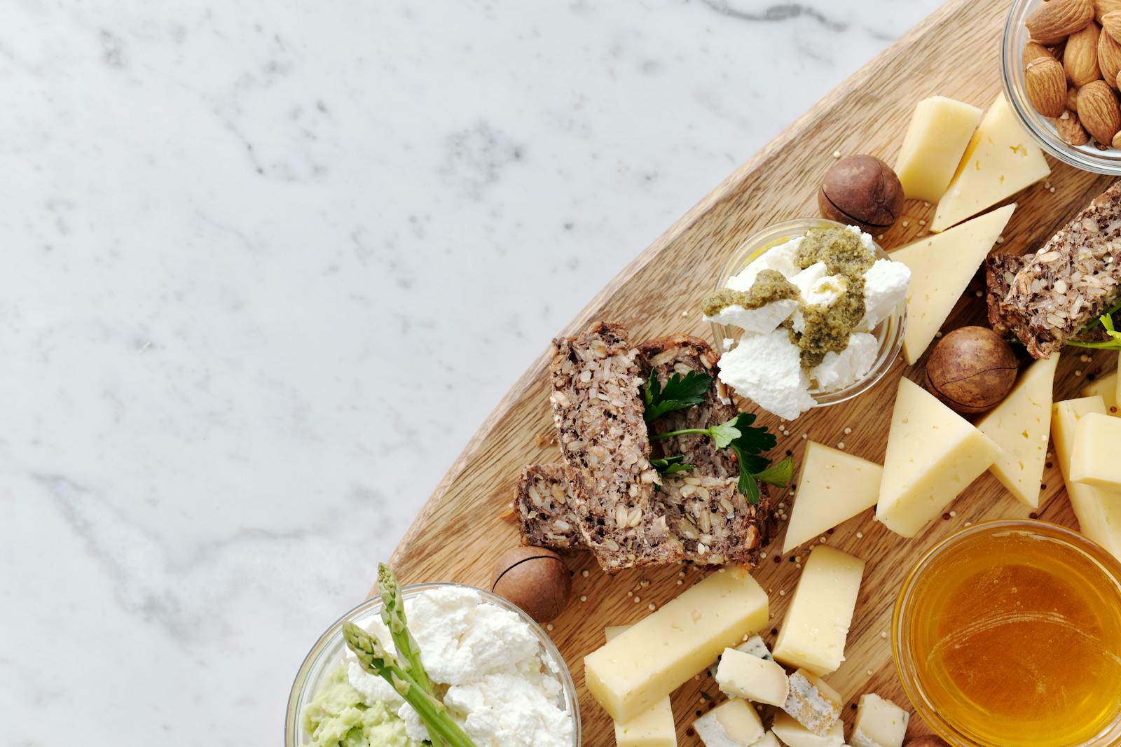 Delicious gourmet cheese platter featuring assorted cheeses, nuts, and honey on a rustic wooden board.