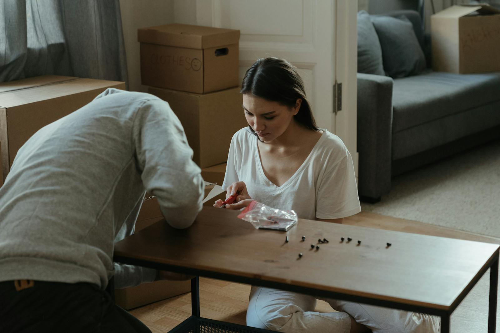Young couple assembling a coffee table in their new home surrounded by moving boxes.