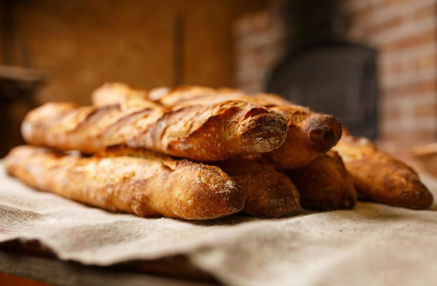 Warm, freshly baked rustic baguettes stacked in a cozy bakery setting.