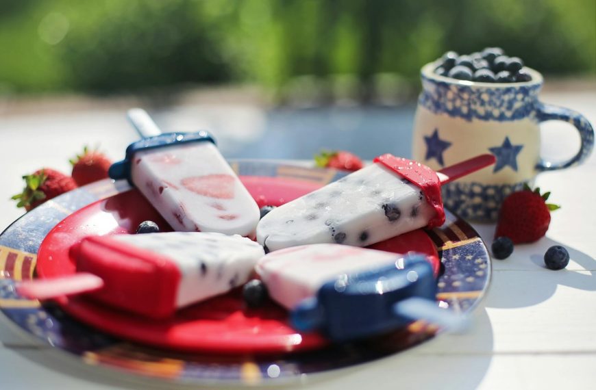Colorful berry popsicles on a plate, perfect for a summer day. Ice cream treats with strawberries and blueberries.