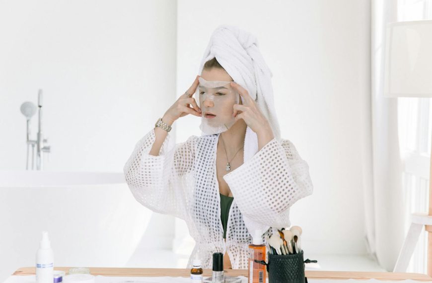 Woman applying a face mask in a bathroom, focusing on skincare and relaxation.