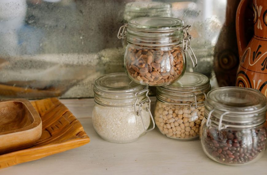 Elegant kitchen scene with glass jars of chickpeas, rice, and beans on a wooden counter.