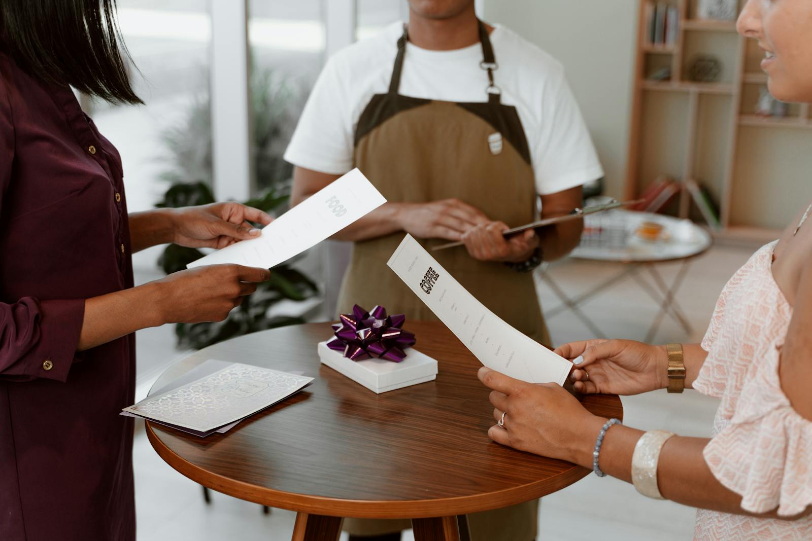 People reviewing a restaurant menu with a gift on a table indoors.