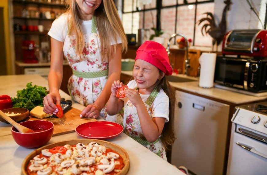 Happy mother and daughter making pizza together in a home kitchen, sharing quality family time.
