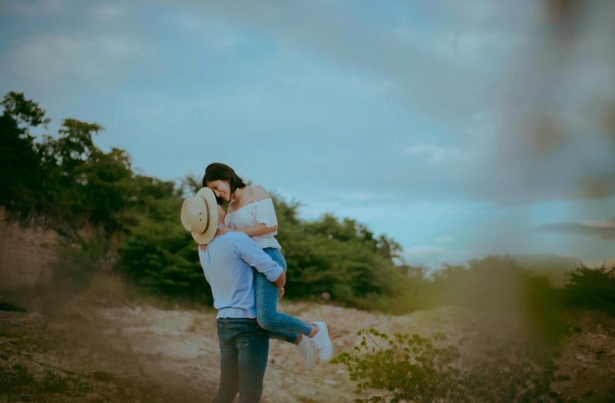 A couple shares a loving embrace outdoors, surrounded by nature. Warm and romantic.
