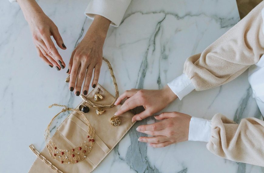 A sophisticated display of gold jewelry and hands on a marble surface, exuding luxury and elegance.