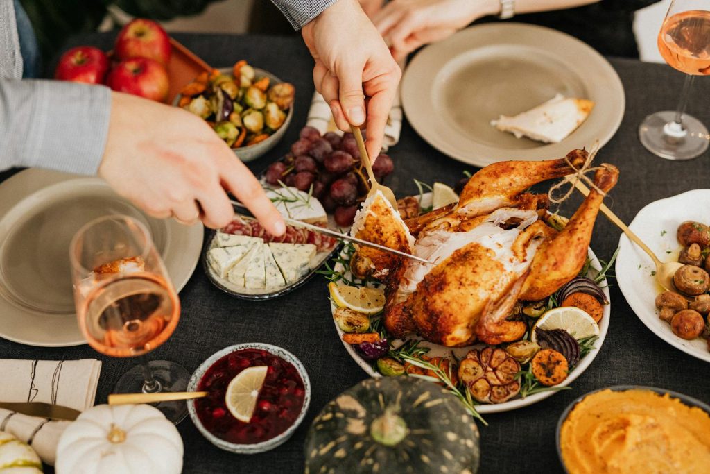 Top view of a festive table with roasted turkey, vegetables, and wine, perfect for Thanksgiving.