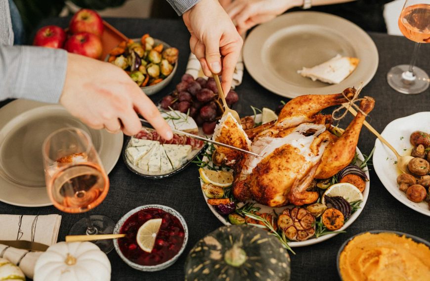Top view of a festive table with roasted turkey, vegetables, and wine, perfect for Thanksgiving.