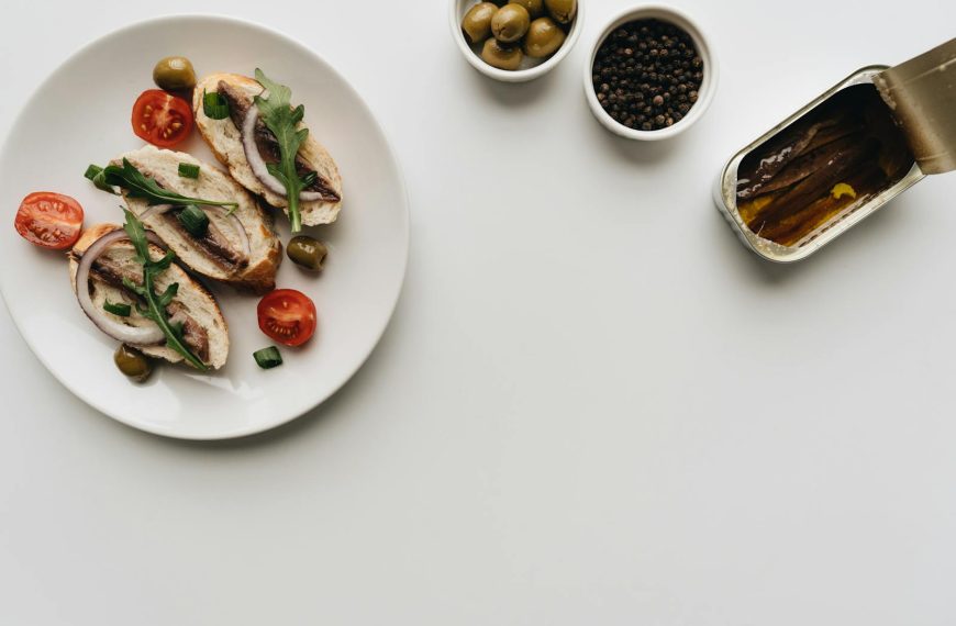 Top view of delicious Mediterranean dish with anchovies, olives, and tomatoes on white background.