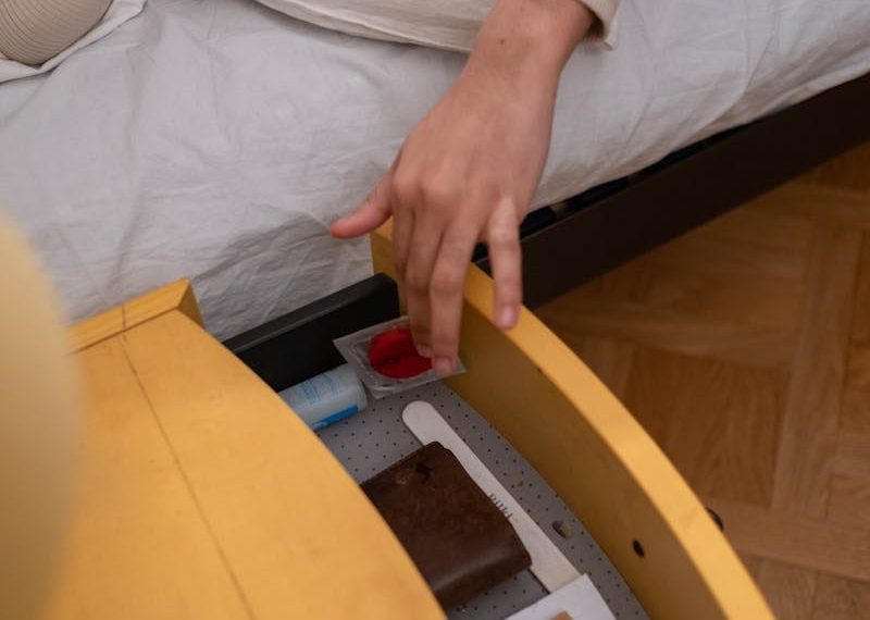 A woman smiling while reaching for a protected item in a bedside drawer.