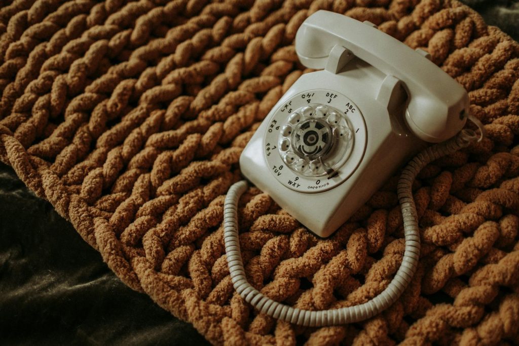 A classic white rotary phone resting on a textured brown mat, showcasing retro charm.