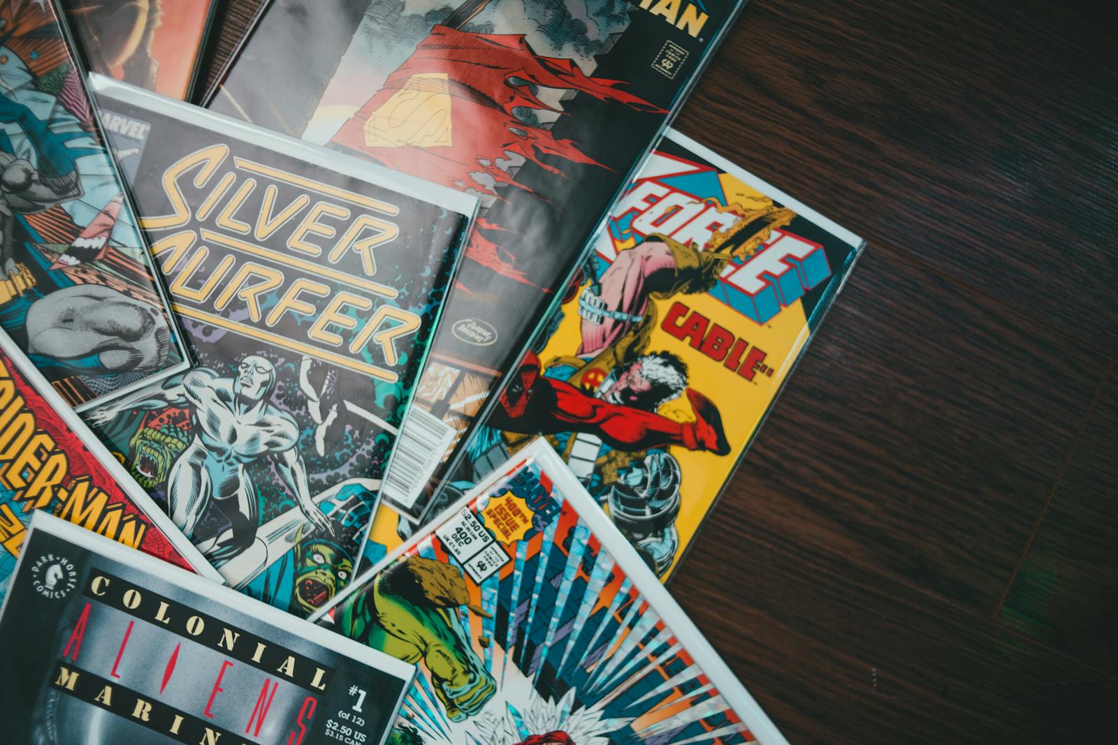 A vibrant assortment of classic comic book covers displayed flat on a wooden surface.