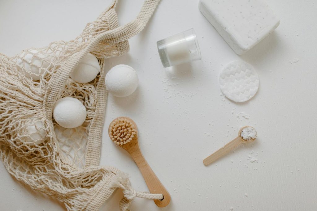 Minimalist flat lay of eco-friendly bath essentials including bath bombs, soap, and a brush.