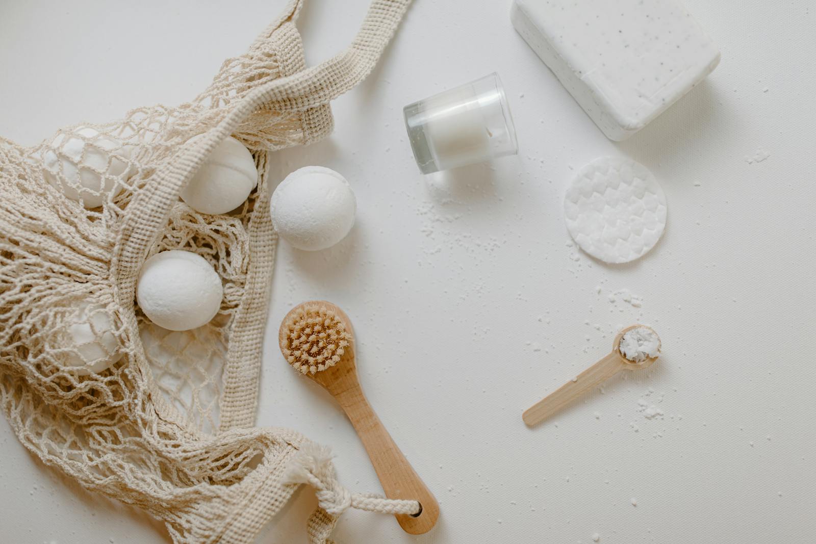 Minimalist flat lay of eco-friendly bath essentials including bath bombs, soap, and a brush.