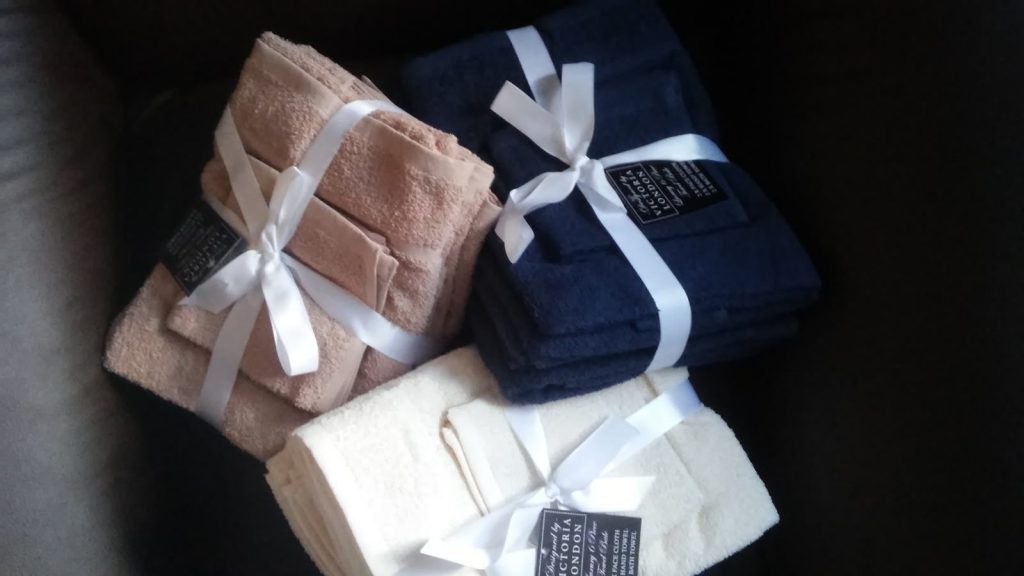 Three bundled sets of bath towels tied with ribbons, showcasing luxury and style.