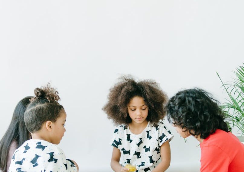 Four children enjoying a creative indoor playtime with paints and crafts in a bright setting.