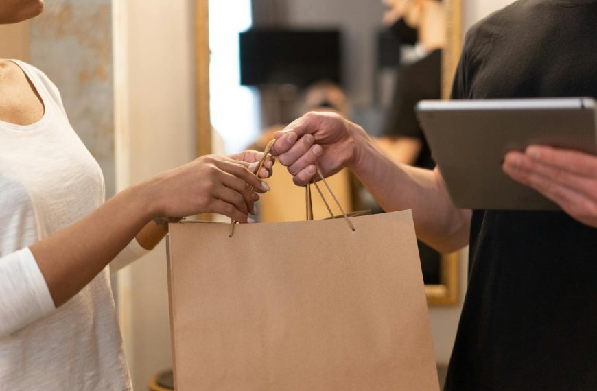Close-up of hands exchanging a shopping bag indoors, symbolizing modern retail and technology.
